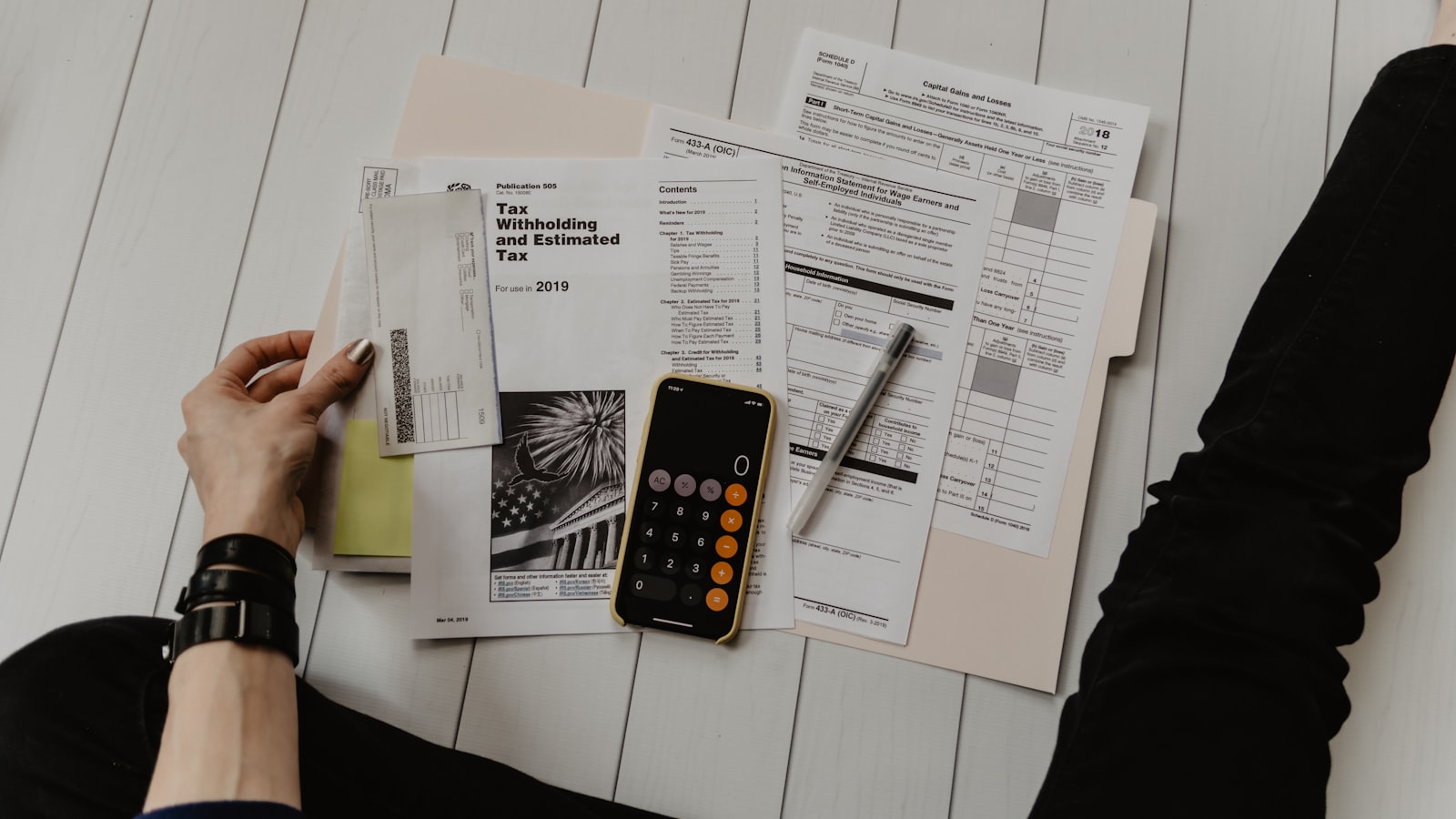 Tax forms, a folder, and a phone calculator spread across a desk