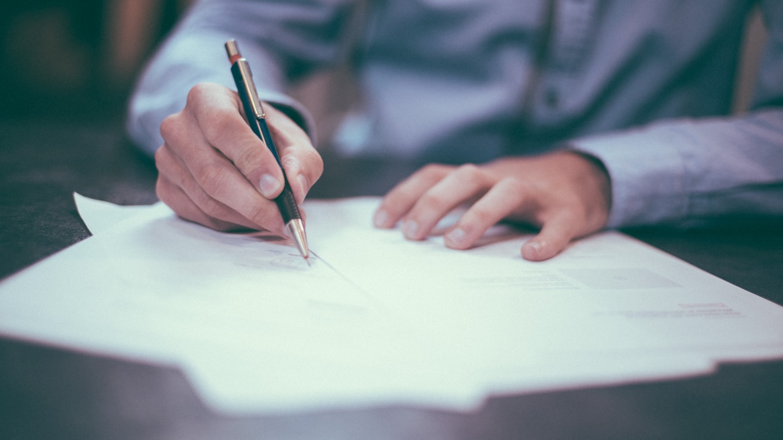 Signing legal documents at a desk with a pen